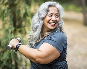 A woman smiles while working out with weights