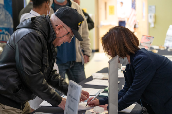A person fills out a form at an information booth.