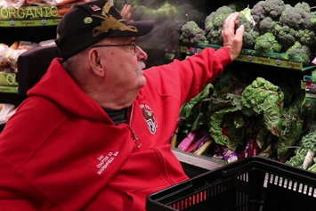 Veteran at the grocery store selecting fresh broccoli  