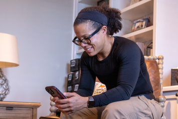 A person looks at their cellphone while sitting in their house.