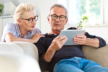 A couple looks at a tablet together in their living room.