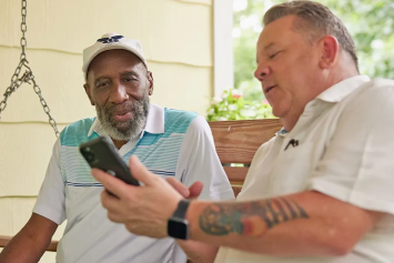 Two Veterans sitting on a porch looking at a smart phone
