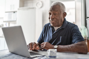 A Veteran looking at his laptop in his home