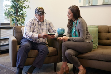 A Veteran and health professional sit together and look at information on a cell phone.