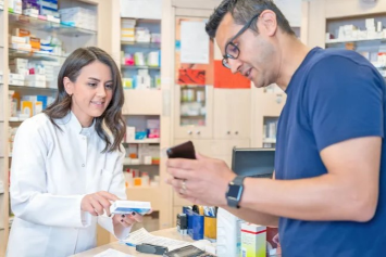 A person shows a pharmacist their prescription info on a mobile phone.
