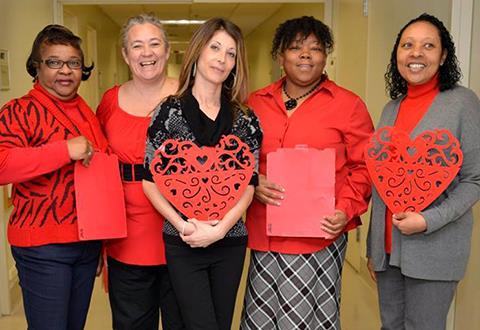 Women dressed in red holding a heart