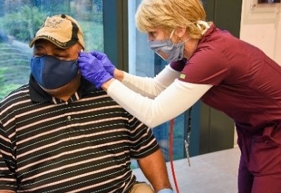 A VA health care provider helping a Veteran with his mask