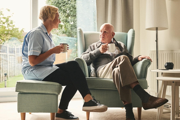 A Veteran sitting and talking with his caregiver at home 