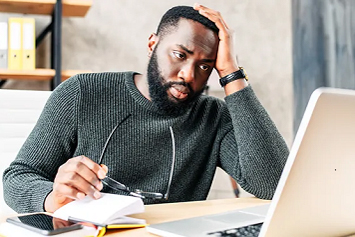 A Veteran looking at his laptop screen holding his head 