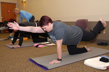 A female Veteran performing stretches in a group class