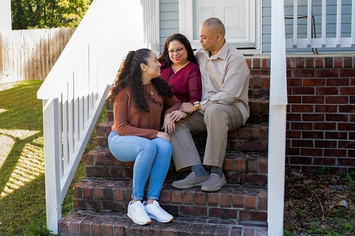 A Veteran sitting with their family on their porch steps