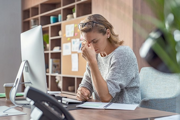 A Veteran sitting at her desk suffering from a headache from her TBI