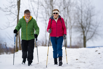A Veteran and their partner using walking sticks for safe exercise on snow
