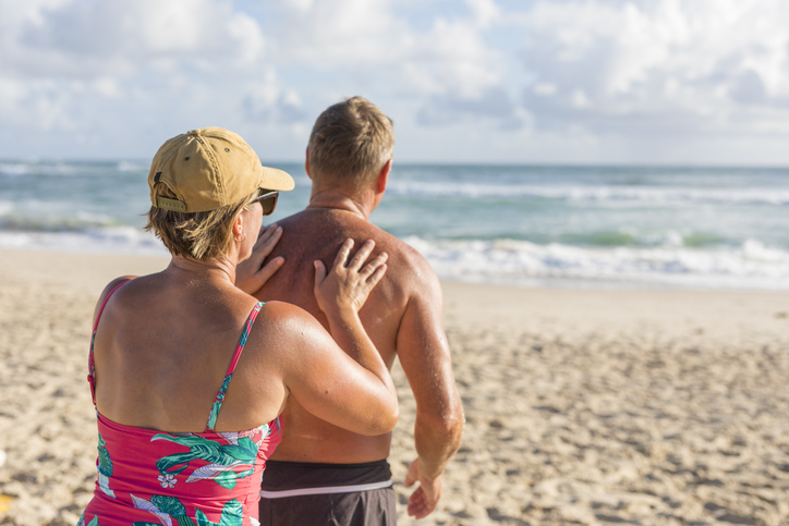 A woman applying sunscreen to her husband to protect him from the sun