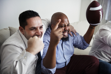 Two Veterans cheering from a sofa while watching a football game