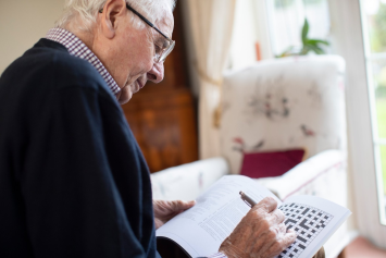 A Veteran doing a crossword puzzle in his home
